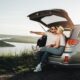 Coppia in viaggio seduta nel bagagliaio di un auto.