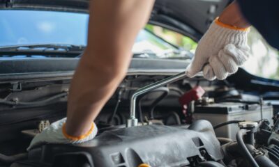 Un meccanico con guanti utilizza una chiave per riparare il motore di un'auto