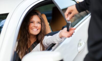 Ragazza sorridente seduta nella sua nuova auto mentre riceve le chiavi