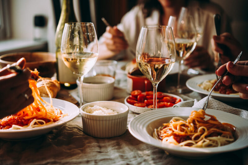 Persone gustano pasta e vino a cena in un ambiente accogliente