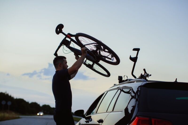 Uomo posiziona una bici sul tetto della sua auto