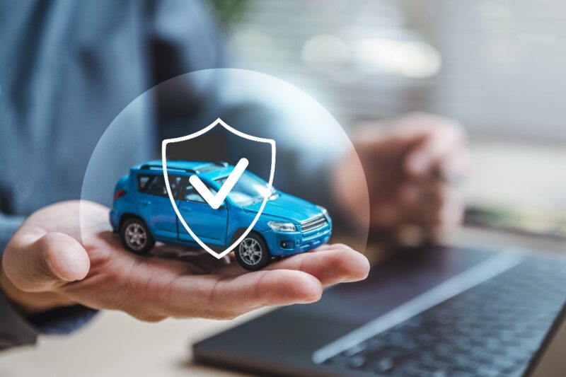 Rappresentazione del concetto di assicurazione auto con modellino di automobile e icona di sicurezza.