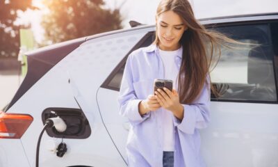 Ragazza al telefono attende ricarica dell'auto elettrica