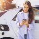 Ragazza al telefono attende ricarica dell'auto elettrica
