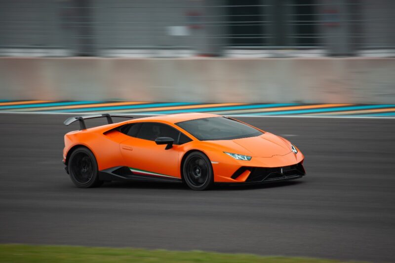 Un'auto sportiva arancione che corre ad alta velocità in circuito.