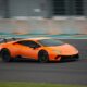 Un'auto sportiva arancione che corre ad alta velocitĂ in circuito.
