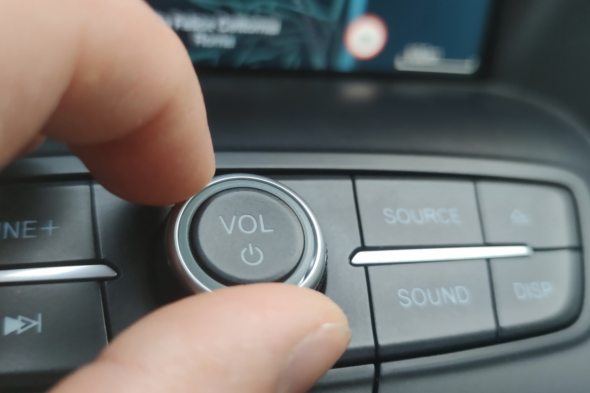 Mano regola il volume di un autoradio
