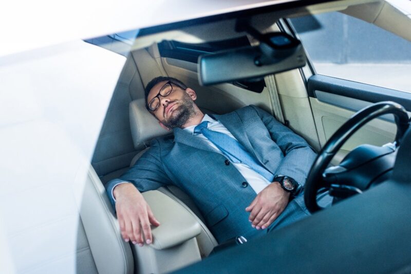 Uomo d'affari stanco che dorme in macchina.