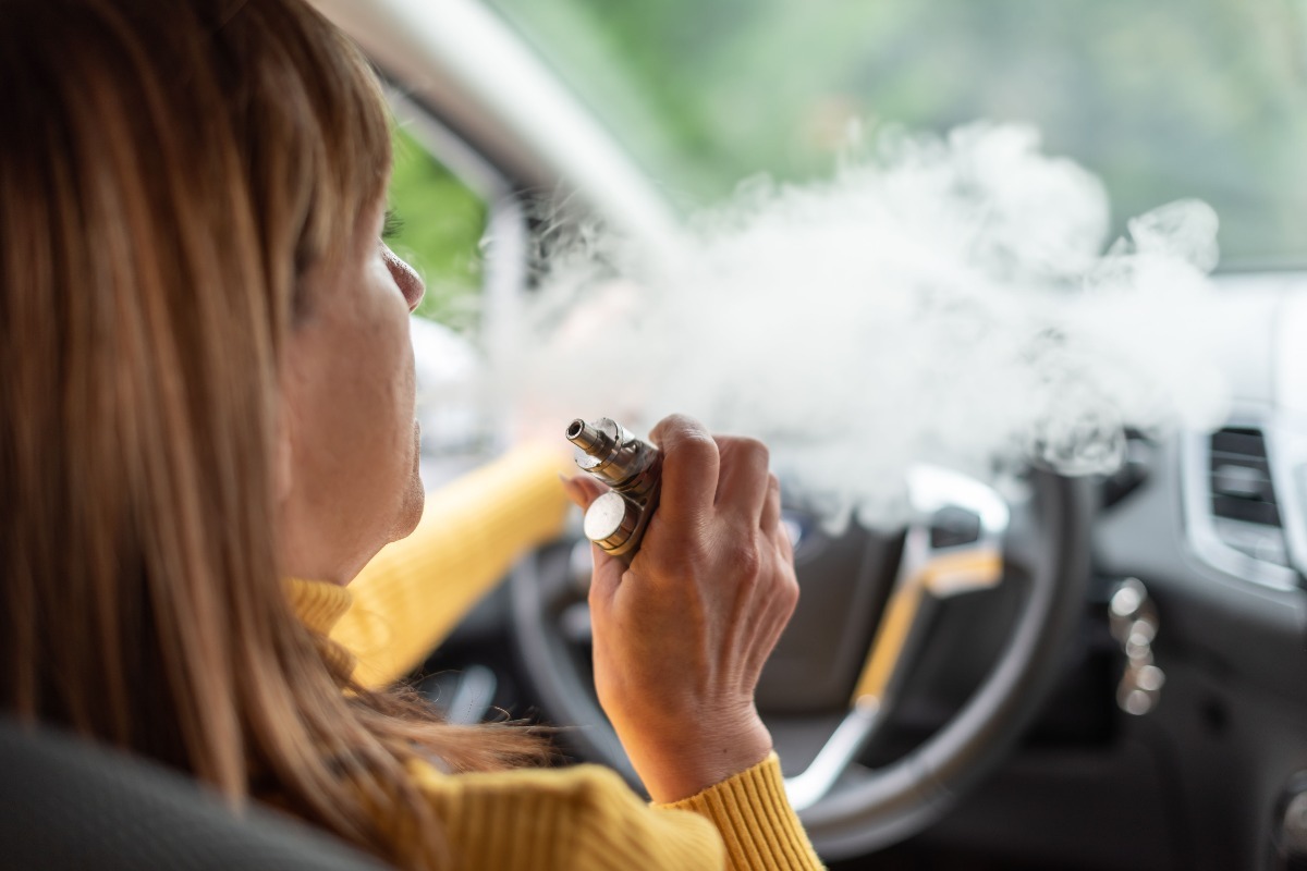 Donna fuma una sigaretta elettronica in auto