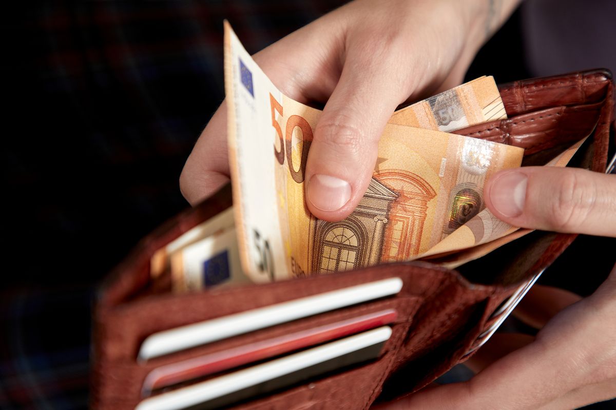 Uomo estrae banconote dal portafoglio