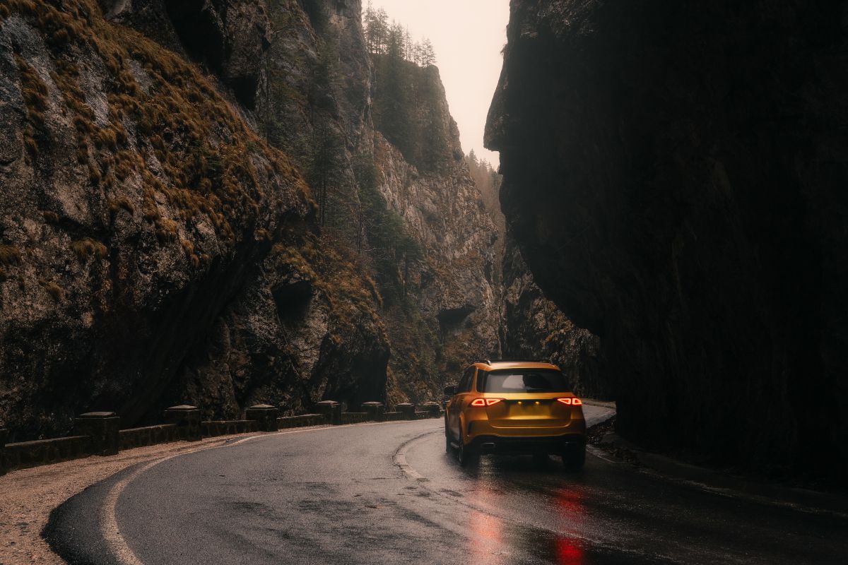 Auto gialla percorre una strada di montagna.