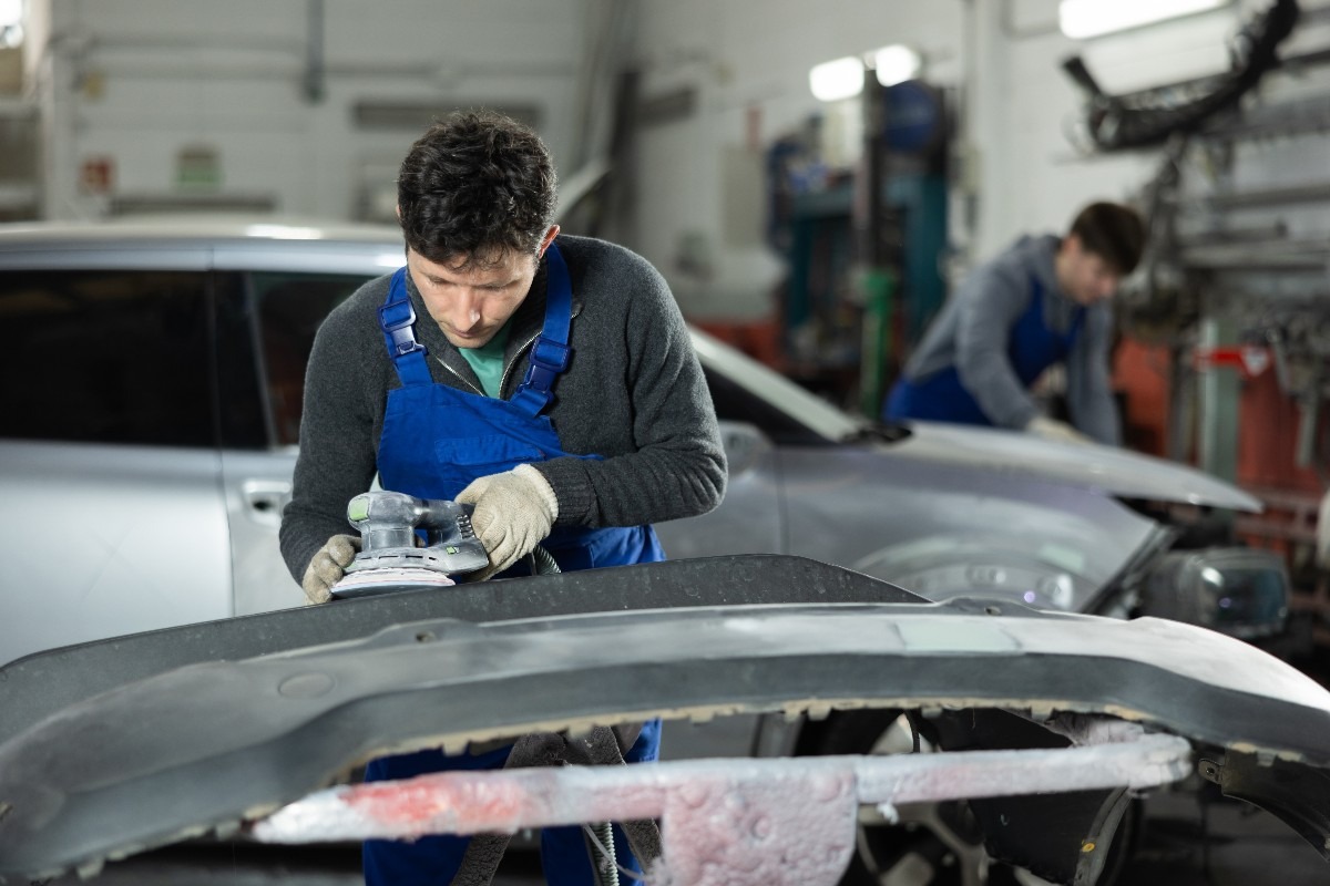 Operaio ripara la carrozzeria di un'auto in officina.