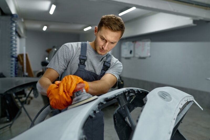 Operaio ripara la carrozzeria di un'auto in officina.