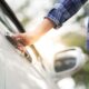Mano di una persona che impugna la maniglia della porta di un'auto.