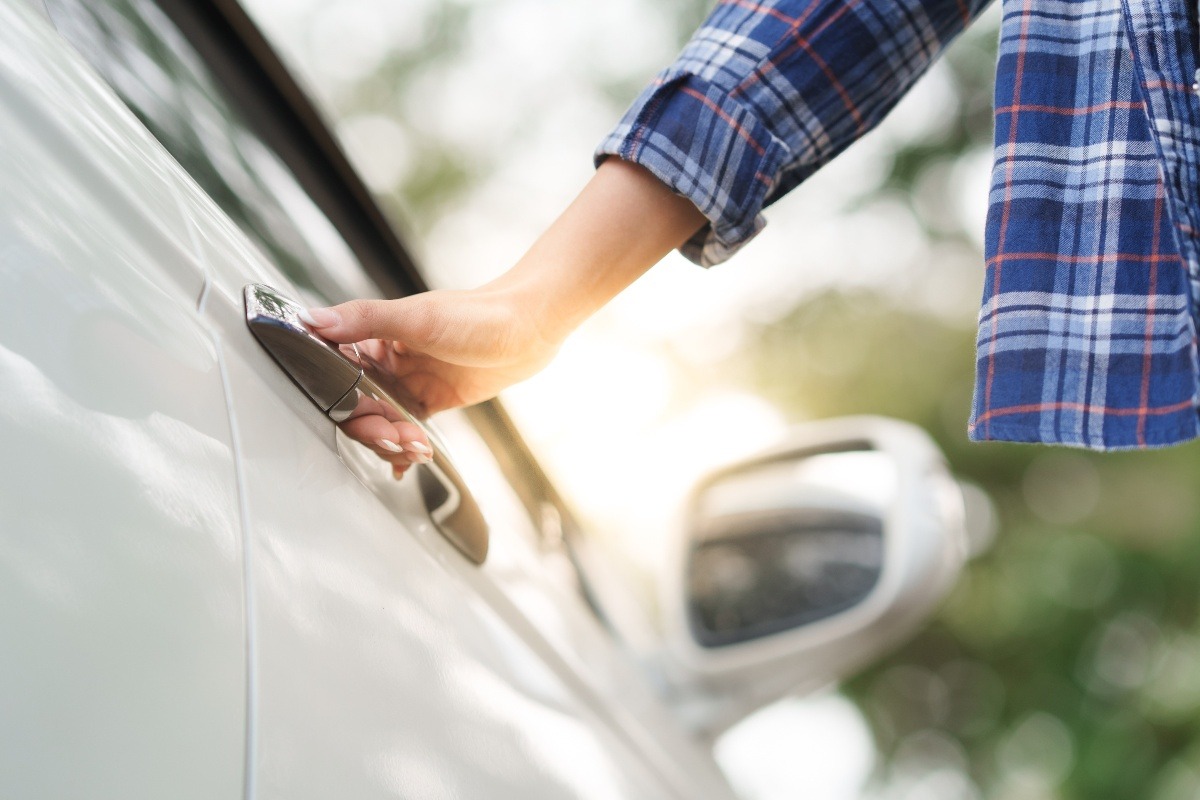 Mano di una persona che impugna la maniglia della porta di un'auto.