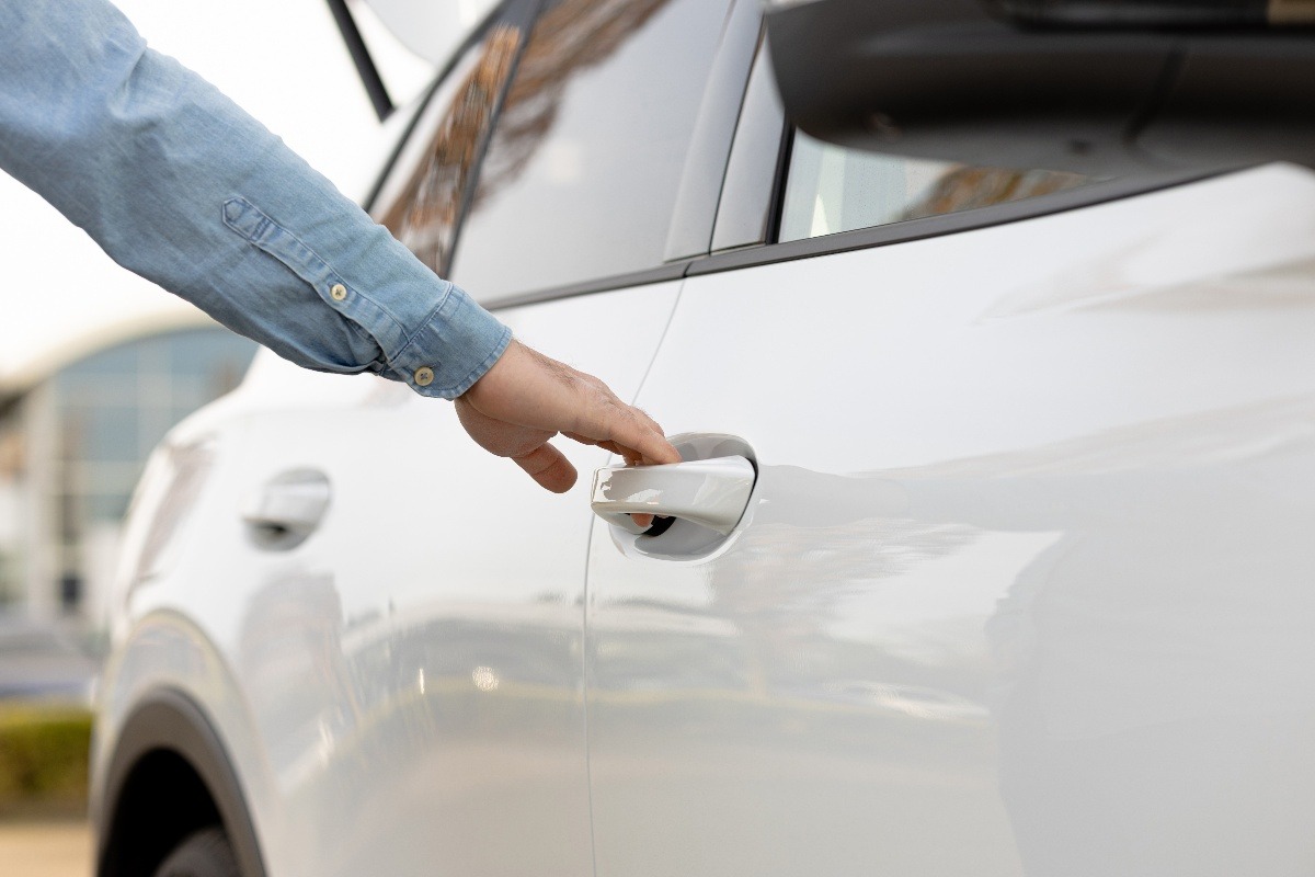Mano di una persona che impugna la maniglia della porta di un'auto.