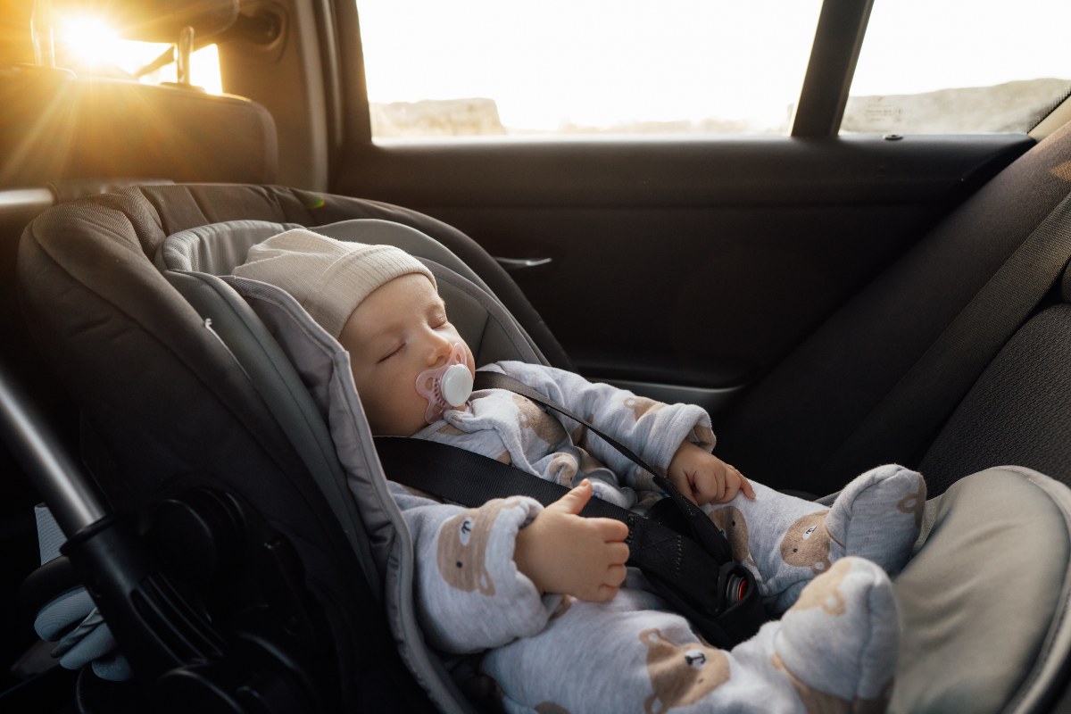 Neonato dorme in un seggiolino auto.