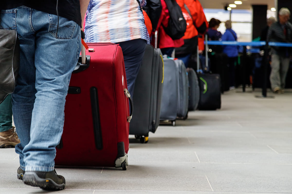 Coda di passeggeri in aeroporto con le loro valigie.